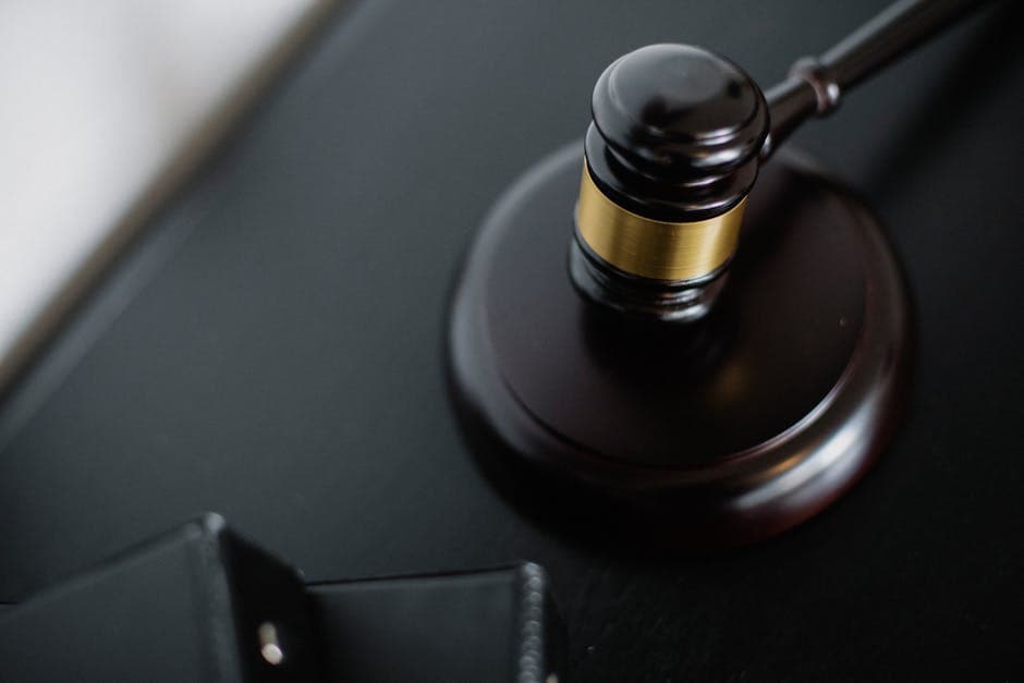 From above of wooden gavel on round surface near folders on table in courtroom