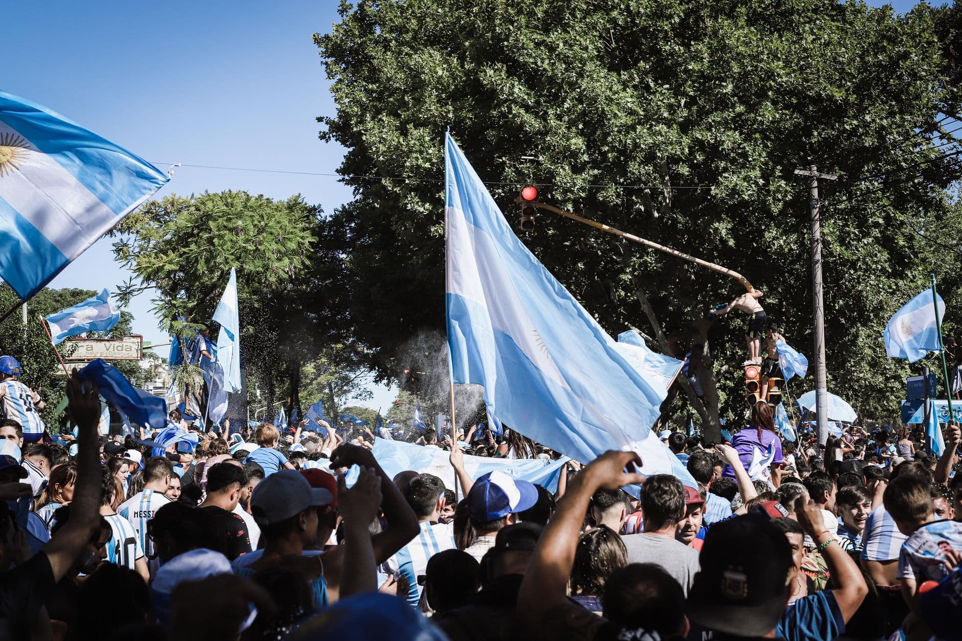Crowd celebrating with Argentine flags in Buenos Aires during a joyful daytime event.